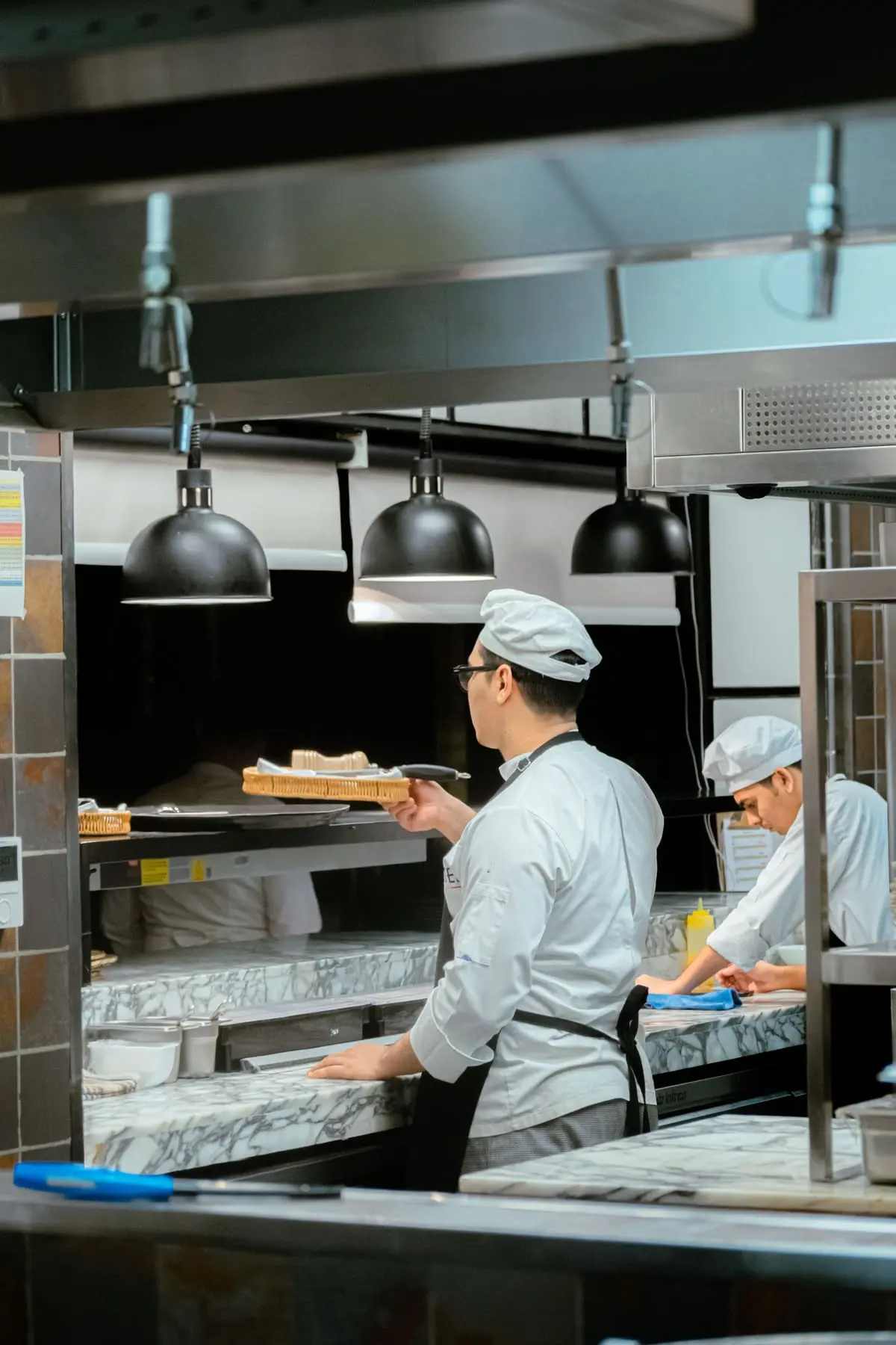 Cuisiniers en service sous le passe inox d'un restaurant, illustration Biohotte Nuisibles, Hauts-de-Seine