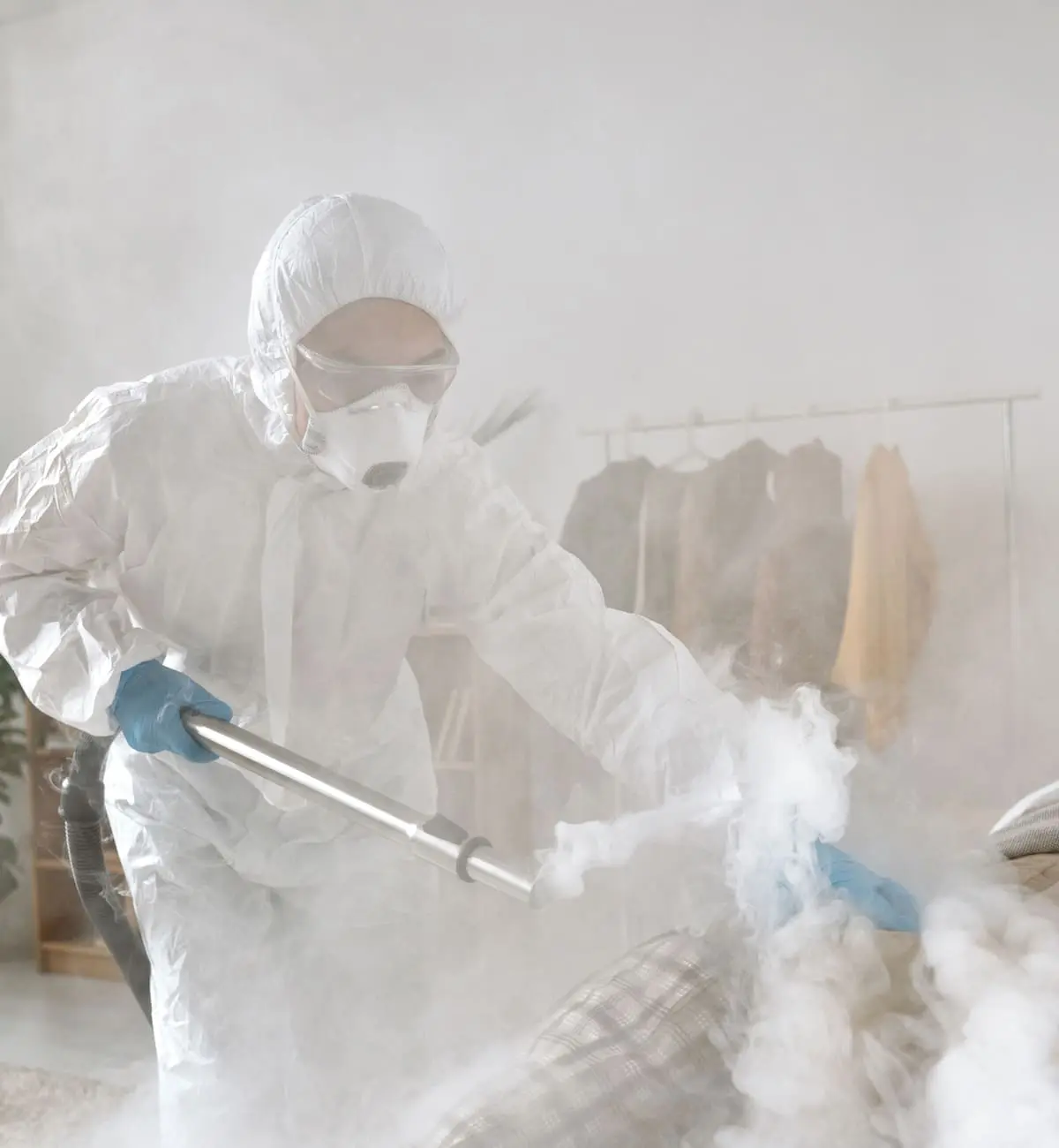 Agent en combinaison et masque passant la vapeur sur un canapé et ses coussins, illustration Biohotte Nuisibles, Nanterre